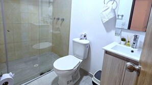 Kylpyhuoneessa on lasiseinällinen suihkukaappi, wc-istuin, peilillä varustettu pesuallas ja puinen kaappi.