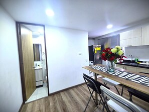 A compact kitchen with a dining area, a refrigerator with notes, a sink, and a vase with flowers on the table. - Perfect 2-bedroom apartment in gorgeous Bogotá D.C. neighborhood (Bogotá, D.C.)