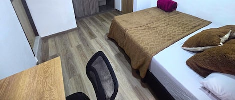 A hotel room with two beds, a desk, a chair, a TV, and a wardrobe.