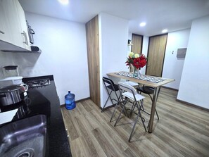 A compact kitchen with a gas stove, a sink, a water dispenser, and a dining area with a table and chairs. - Perfect 2-bedroom apartment in gorgeous Bogotá D.C. neighborhood (Bogotá, D.C.)