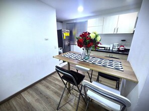 A dining area with a table, chairs, a vase with flowers, and a kitchen in the background. - Perfect 2-bedroom apartment in gorgeous Bogotá D.C. neighborhood (Bogotá, D.C.)