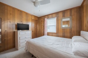 A bedroom with a bed, a dresser, a television on top, a window with blinds, and a ceiling fan. - 4755 - The OBX Rx, Semi-oceanfront! (Kitty Hawk)