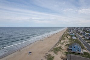 A beach with a sandy shore, a few umbrellas, and houses along the coastline. - 4755 - The OBX Rx, Semi-oceanfront! (Kitty Hawk)