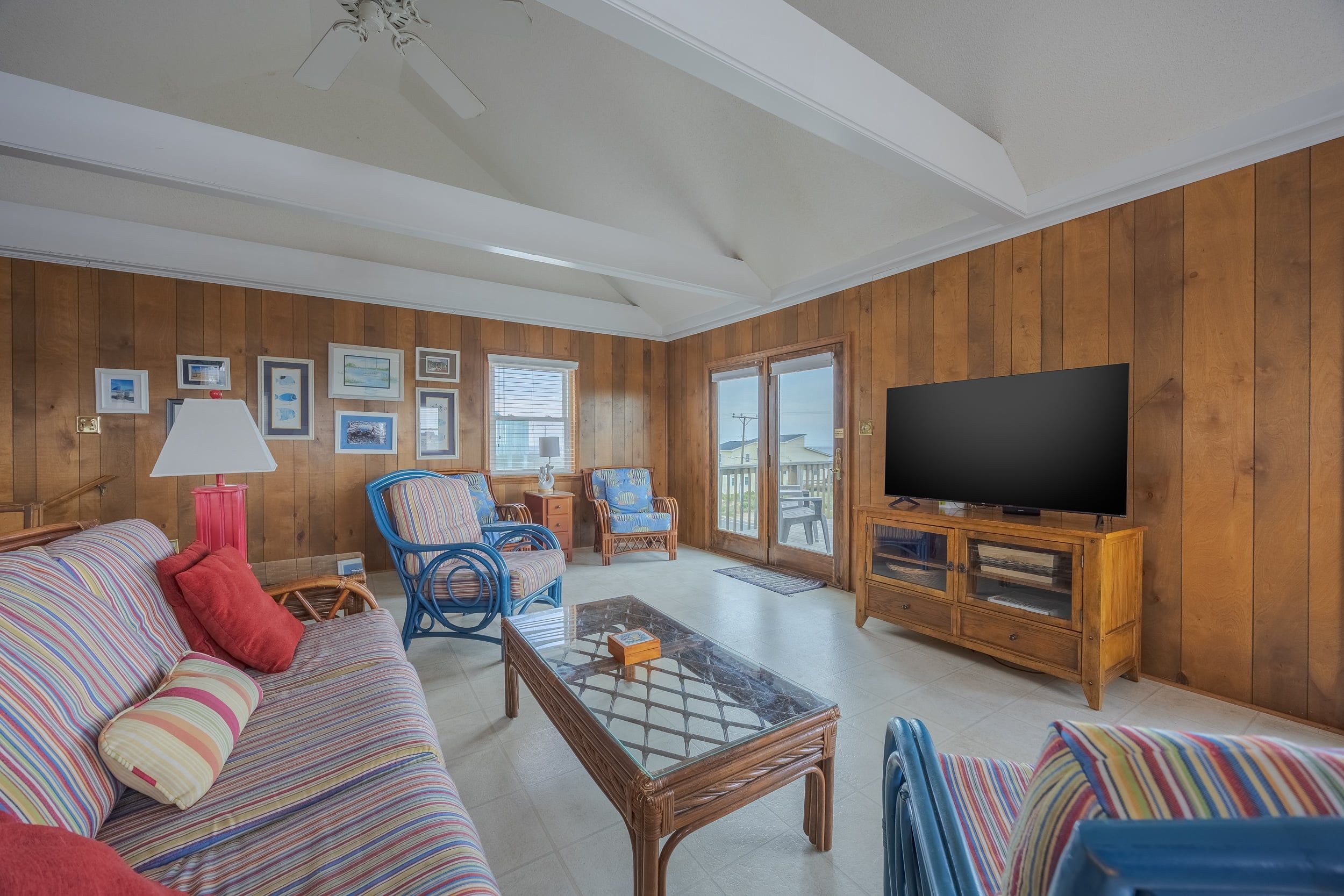 A living room with a sofa, chairs, a coffee table, a television, and a wooden paneled wall.
