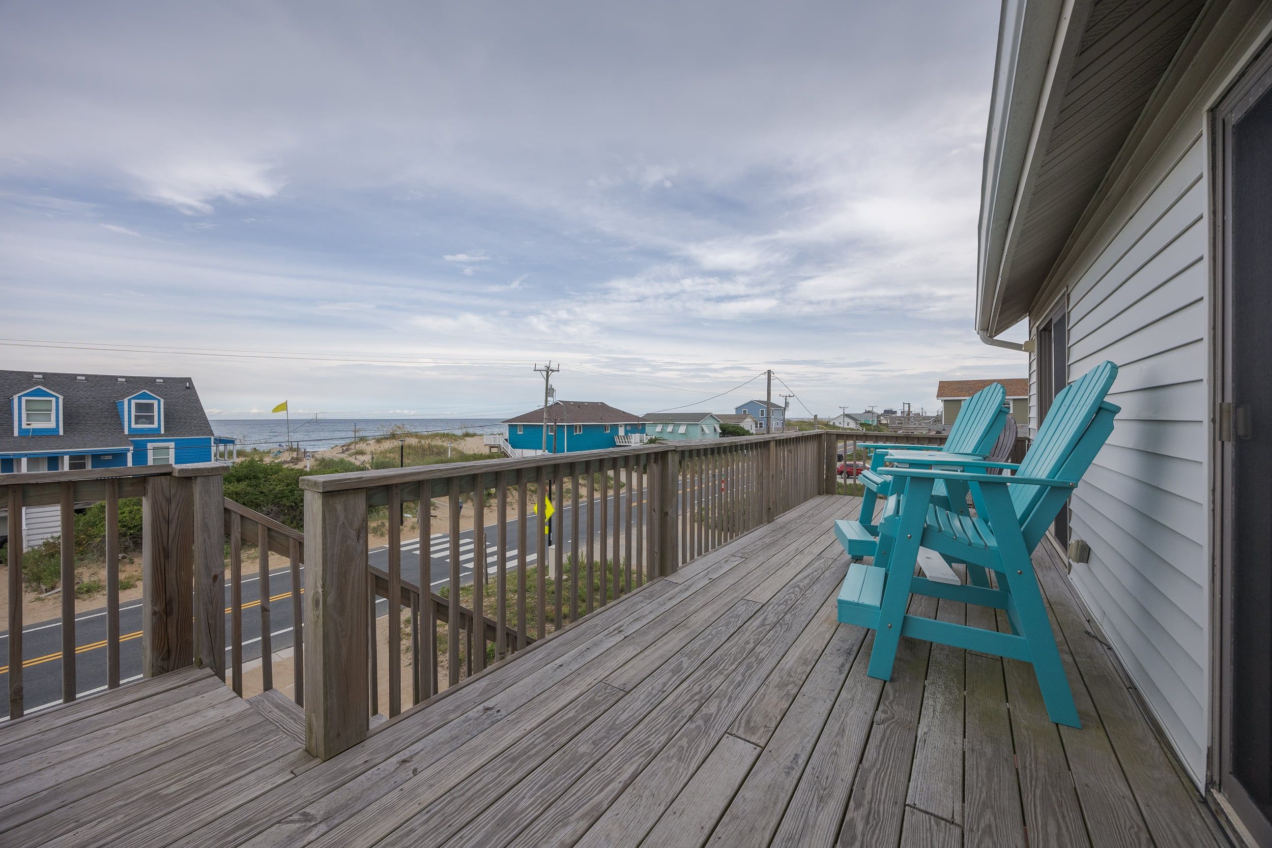 A wooden deck with a view of the beach and ocean.