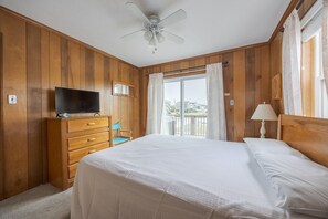A hotel room with a bed, a television, a dresser, a chair, and a balcony with a view. - 4755 - The OBX Rx, Semi-oceanfront! (Kitty Hawk)