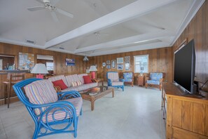 A living room with a sofa, chairs, a coffee table, a television, and wooden walls. - 4755 - The OBX Rx, Semi-oceanfront! (Kitty Hawk)