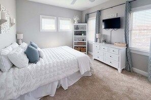 Ein Schlafzimmer mit einem Bett, einem Schminktisch, einem Fernseher und einem Regal mit Dekorationen.