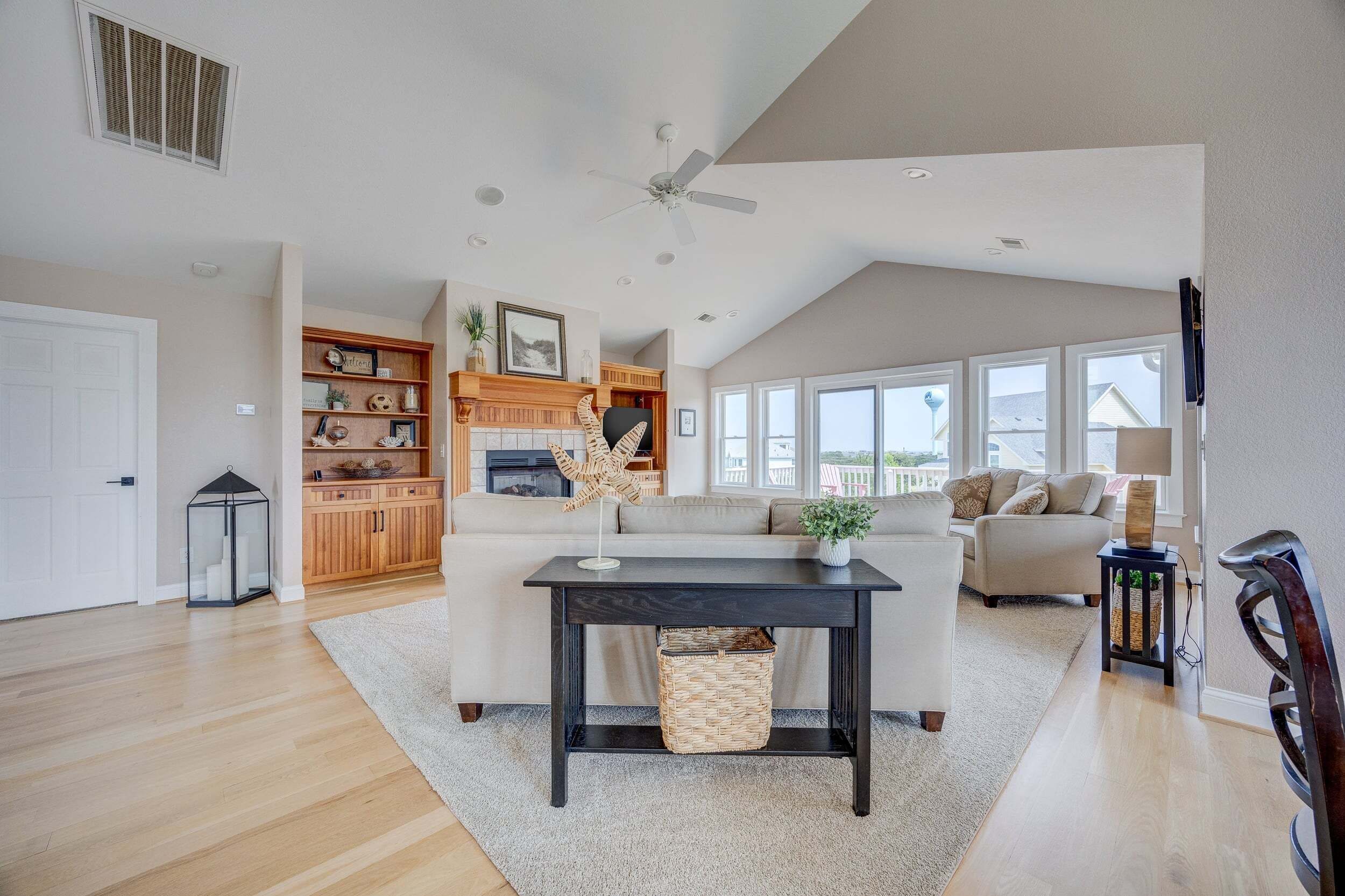 A spacious living area with a fireplace, a sofa, a coffee table, and a view of the outdoors.