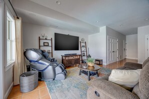 A living room with a reclining chair, a flat-screen TV, a coffee table, and a sofa. - 1822 - Our Happy Place By The Sea, Corolla Retreat | Saltwater Pool & Arcade Game (Corolla)