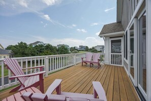 A wooden deck with two Adirondack chairs, a white railing, and a view of houses in the background. - 1822 - Our Happy Place By The Sea, Corolla Retreat | Saltwater Pool & Arcade Game (Corolla)