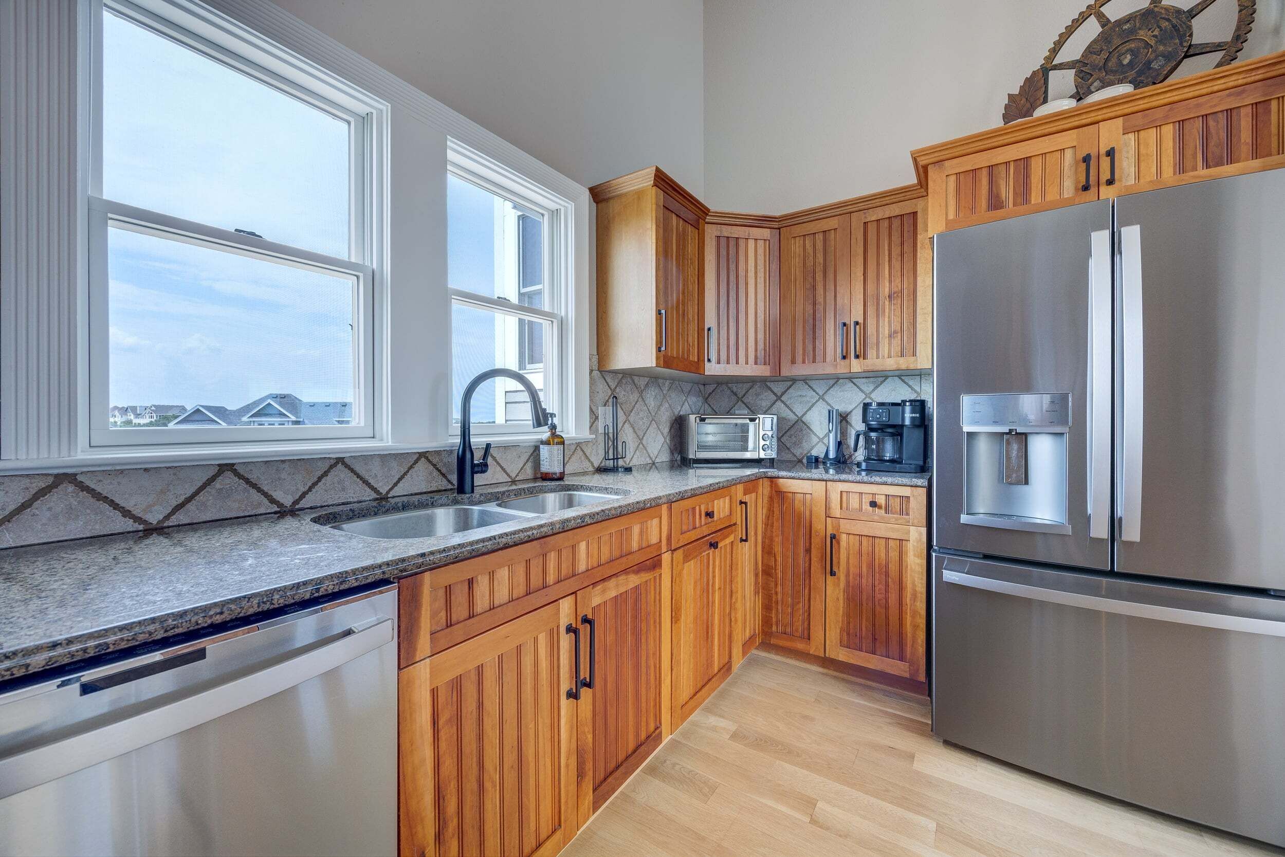 A kitchen with wooden cabinets, a stainless steel refrigerator, a microwave, and a coffee maker.