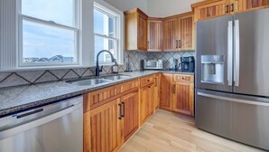 A kitchen with wooden cabinets, a stainless steel refrigerator, a microwave, and a coffee maker. - 1822 - Our Happy Place By The Sea, Corolla Retreat | Saltwater Pool & Arcade Game (Corolla)