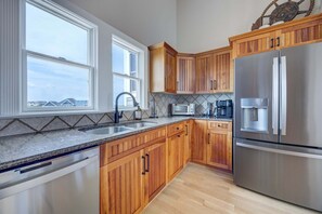 Eine Küche mit Holzschränken, einem Edelstahl-Kühlschrank, einer Mikrowelle und einer Kaffeemaschine.