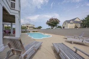 A residential area with a swimming pool, lounge chairs, and houses. - 1822 - Our Happy Place By The Sea, Corolla Retreat | Saltwater Pool & Arcade Game (Corolla)