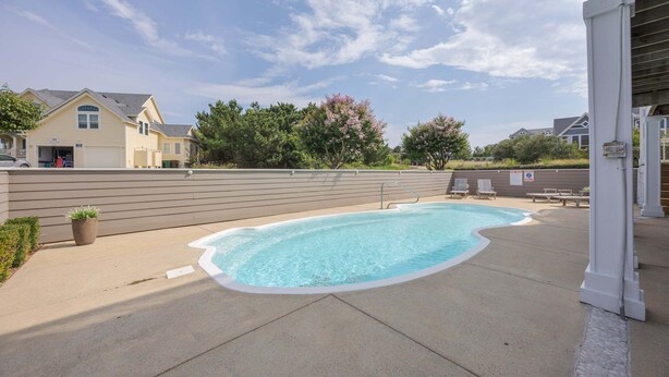 A swimming pool with a clear blue water, surrounded by a concrete deck. - 1822 - Our Happy Place By The Sea, Corolla Retreat | Saltwater Pool & Arcade Game (Corolla)