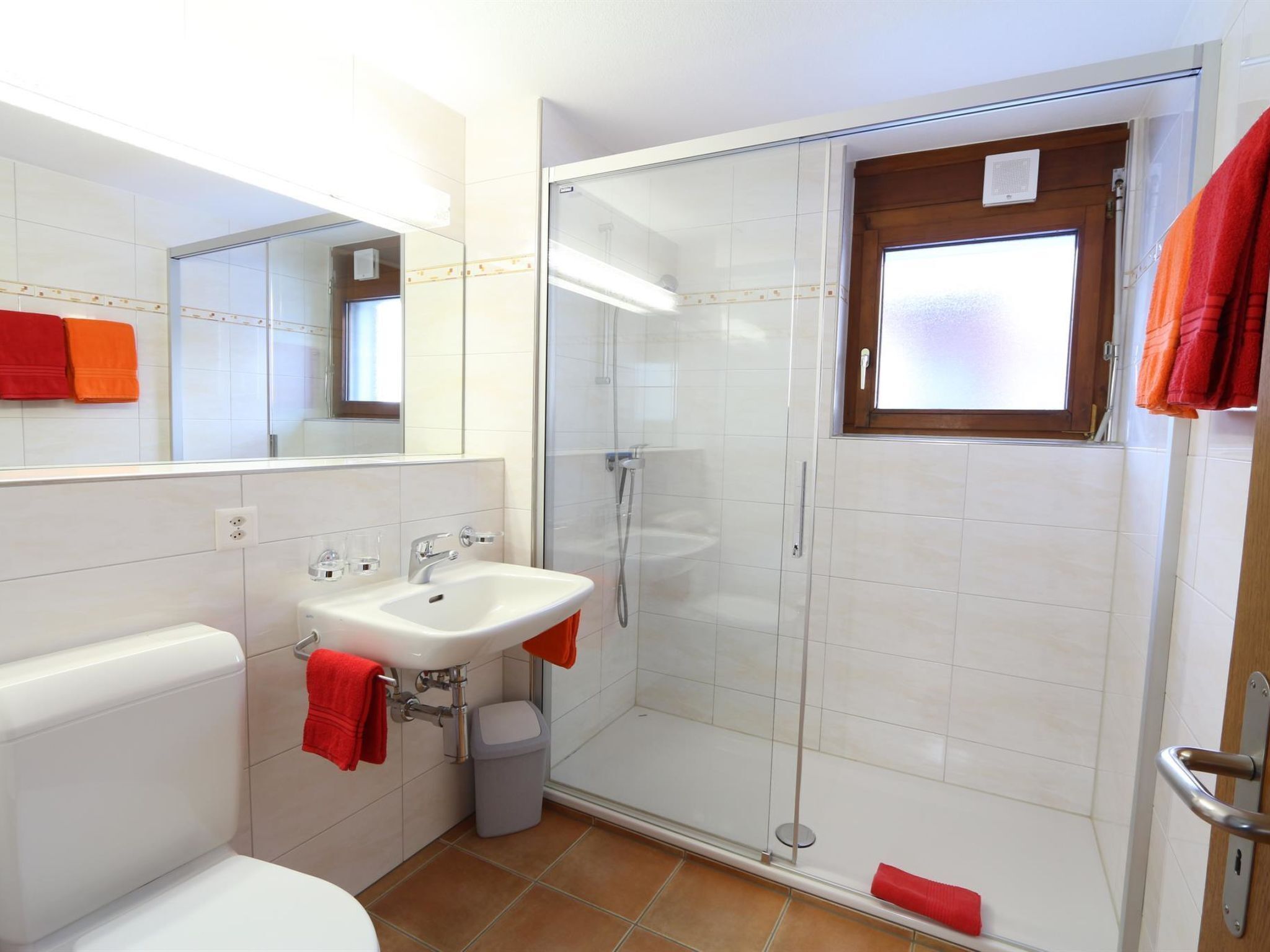 A bathroom with a white sink, a glass-enclosed shower, and a toilet.