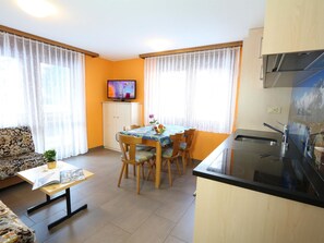 Ein kompakter Wohnbereich mit Essplatz, Küchenzeile und einem an der Wand befestigten Fernseher.