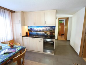 Eine kompakte Küche mit Essbereich, ausgestattet mit Schränken, einer Spüle und einem Backofen.