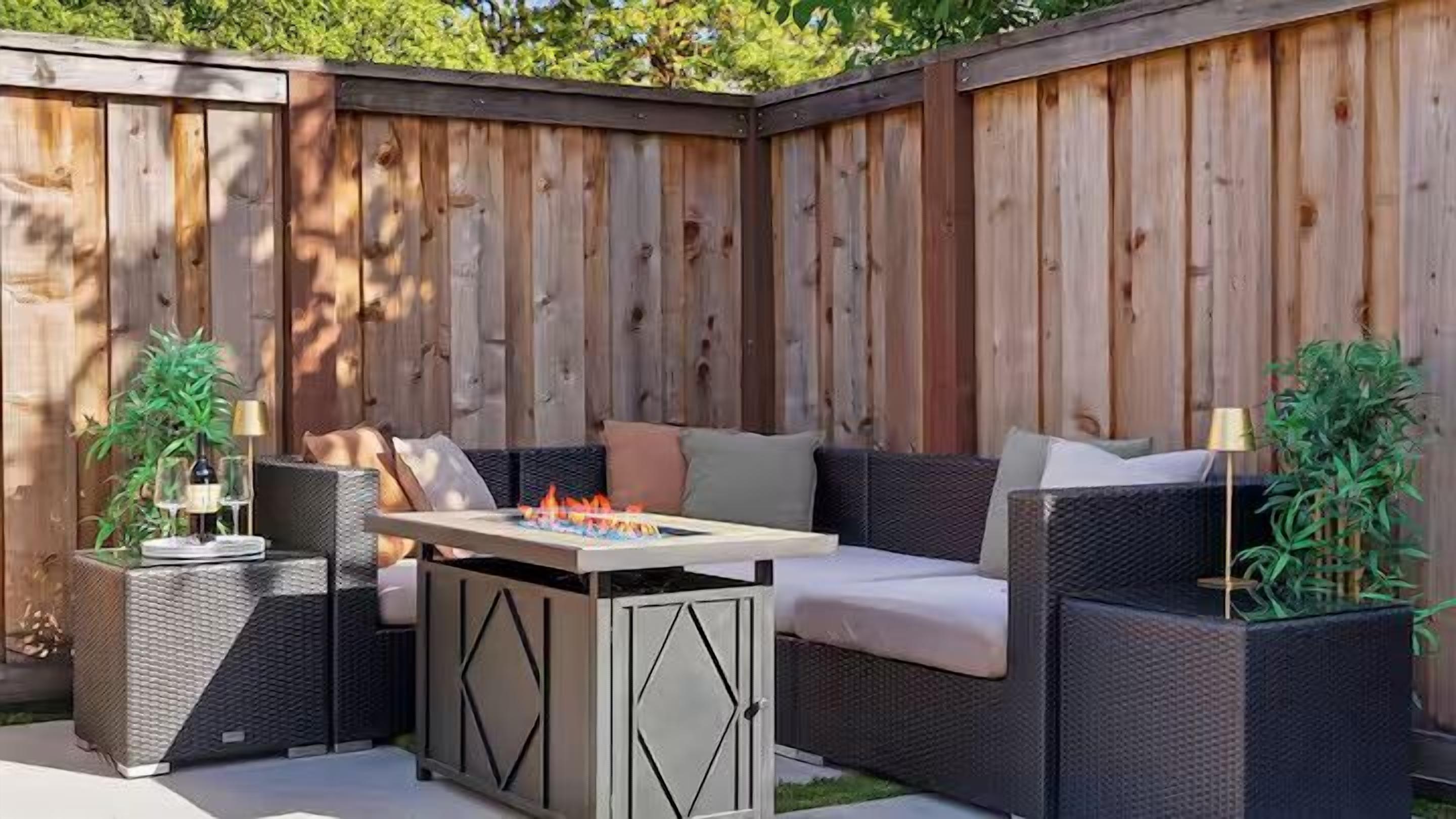 Um pátio externo com mesa de jantar, móveis de vime e plantas em vasos.