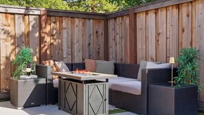 Eine Terrasse im Freien mit Esstisch, Korbmöbeln und Topfpflanzen.