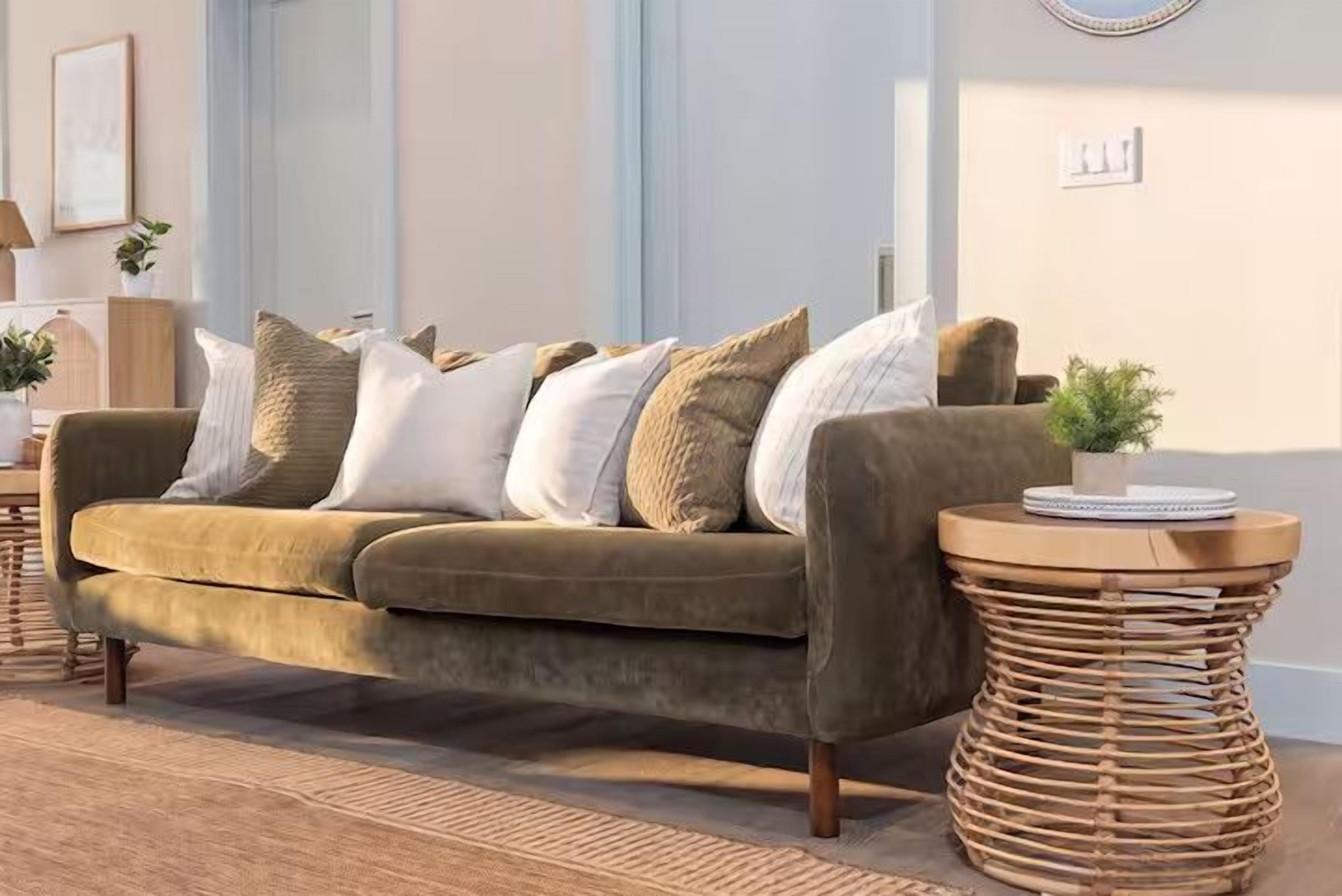 A living room with a sofa, cushions, a round side table, and a small plant.