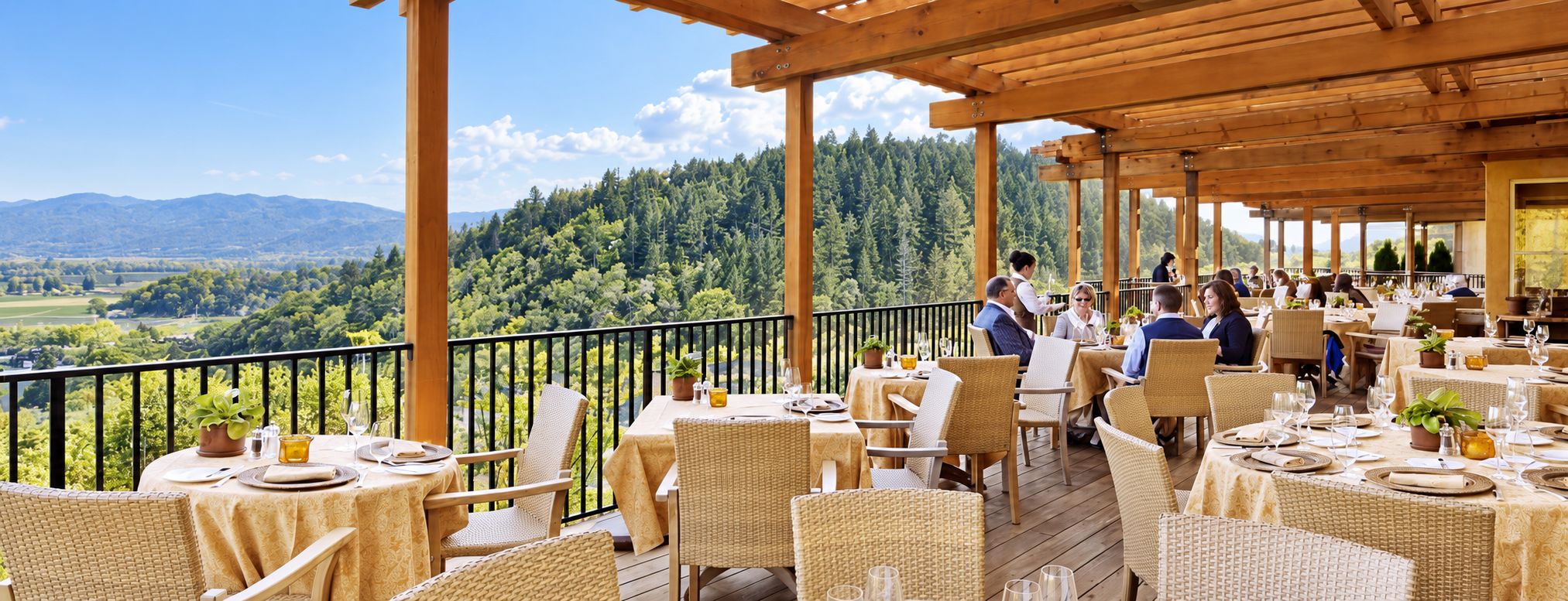 An outdoor dining area with tables and chairs, overlooking a forested landscape.