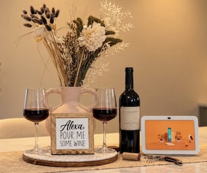 A bottle of wine, two wine glasses, a vase with flowers, a sign, and a tablet on a table. - Casa Solara: Modern Luxury. Spa. Fire Pit - Minutes to Downtown Napa (Napa)
