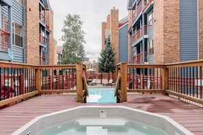 A rooftop pool area with a hot tub, surrounded by brick buildings with balconies. - Upscale Condo in Downtown with Ski In Access, Pool, Hot Tubs, Fitness Center (Breckenridge)