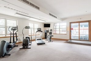 A gym with cardio machines, a television, and large windows. - Upscale Condo in Downtown with Ski In Access, Pool, Hot Tubs, Fitness Center (Breckenridge)