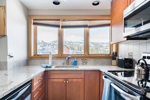 A kitchen with a large window, a dishwasher, a stove, and a toaster. - Peak 9 Inn 4512: Stellar Views - Downtown & Ski In Ski Out @ Base of Peak 9 (Breckenridge)