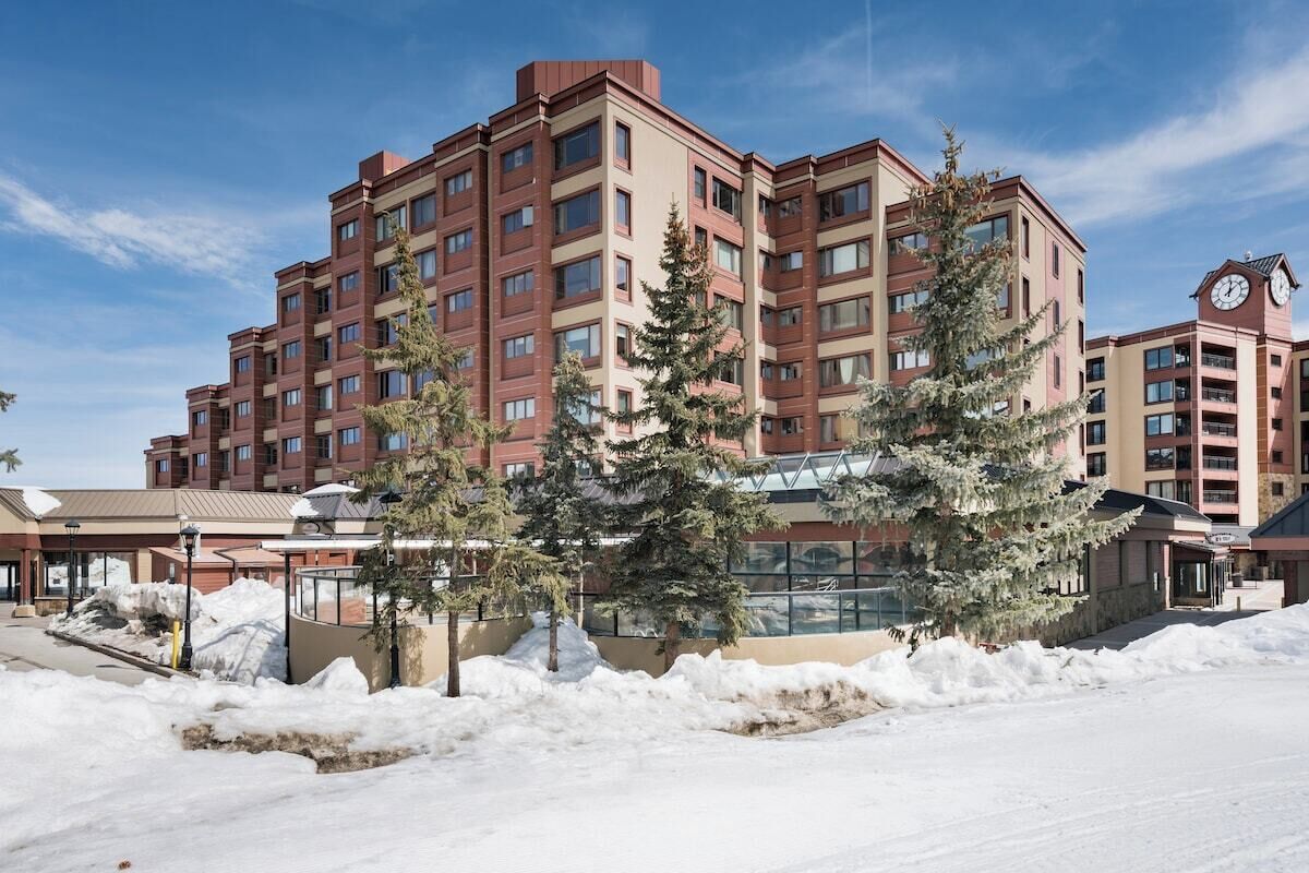A multi-story hotel with a snow-covered ground, a clock tower, and a central courtyard with trees.