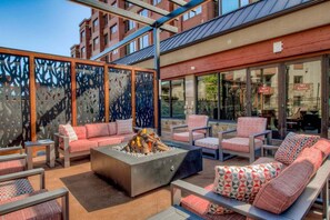 An outdoor seating area with sofas and chairs, a fire pit, and a view of a building with barred windows. - Peak 9 Inn 4512: Stellar Views - Downtown & Ski In Ski Out @ Base of Peak 9 (Breckenridge)