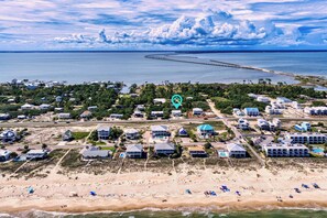 An aerial view of a coastal residential area with houses, a beach, and a pier extending into the water. - Key Lime Cottage - 250 Steps to Beach, Beach Gear Credit Included, Recent Renovations (St. George Island)