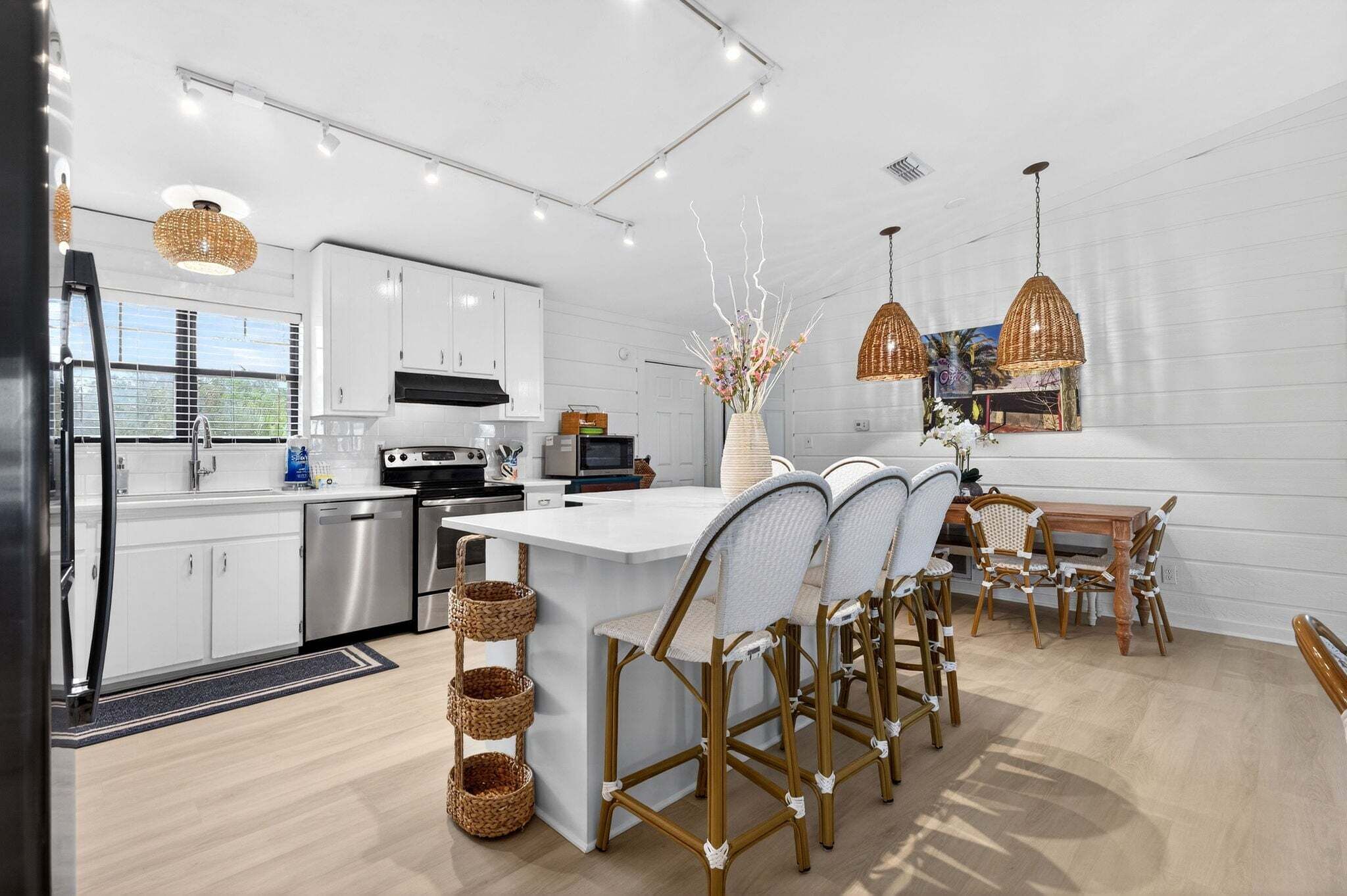 A modern kitchen with white cabinets, stainless steel appliances, and a central island with bar stools.