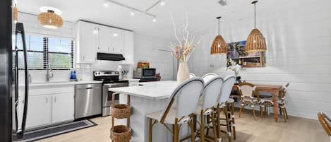 A modern kitchen with white cabinets, stainless steel appliances, and a central island with bar stools.