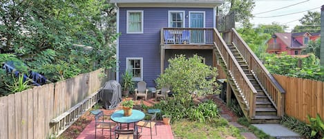 A two-story house with a covered patio area, a wooden staircase, and a fenced backyard.