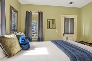 A hotel room with a bed, a large window with curtains, a door, and a mirror on the wall. - Savannah Home, Walkable to Forsyth, Historic (Savannah)
