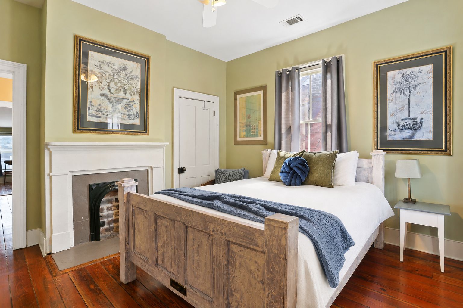 Een slaapkamer met een houten bed, een open haard en kunstwerken aan de wanden.