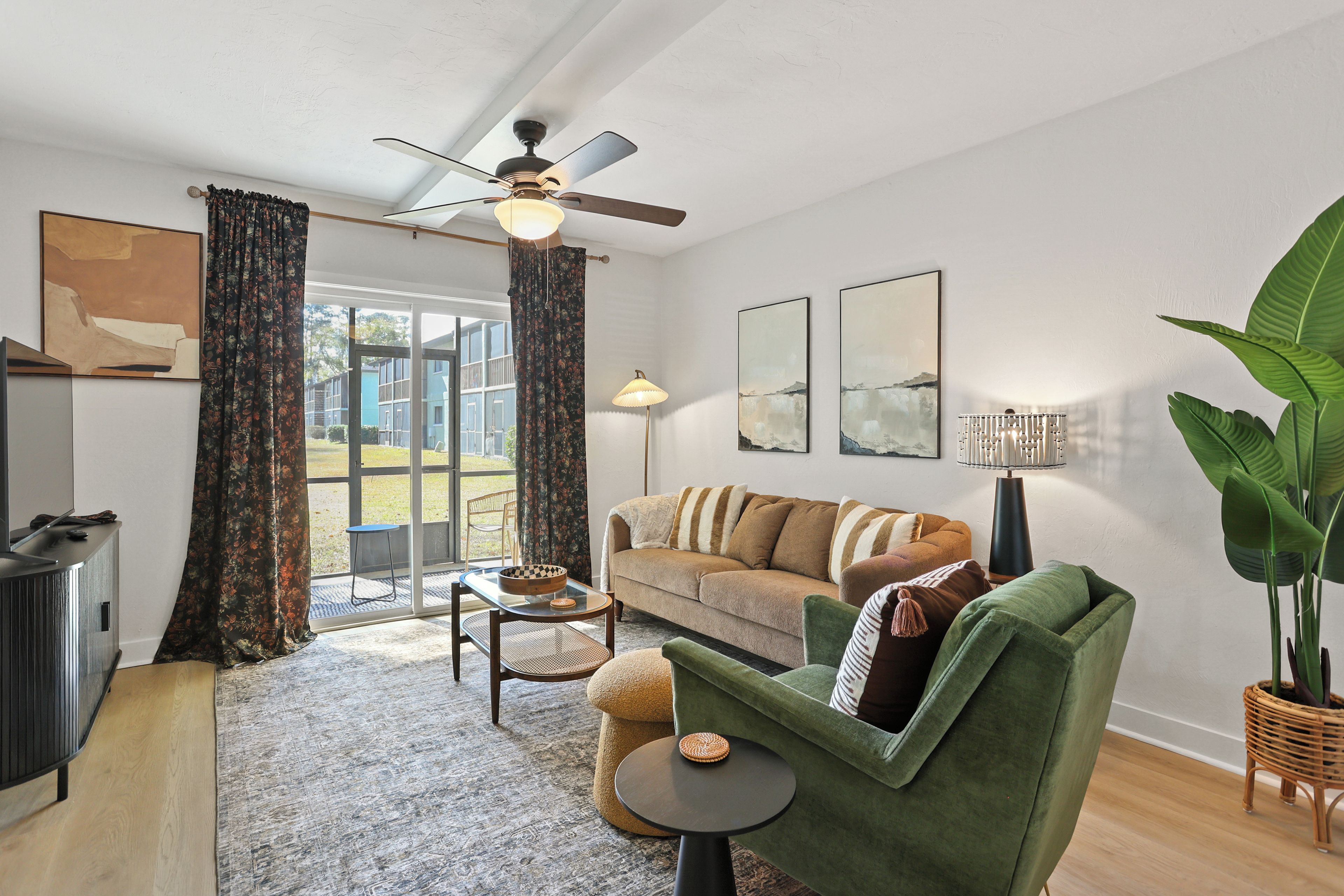 Ein modernes Wohnzimmer mit Sofa, Sessel, Couchtisch und Deckenventilator.