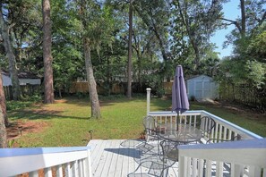 A deck with outdoor furniture, surrounded by trees and a wooden fence. - Fun Family Friendly 3bd/2ba Near Tybee & Savannah (Savannah)