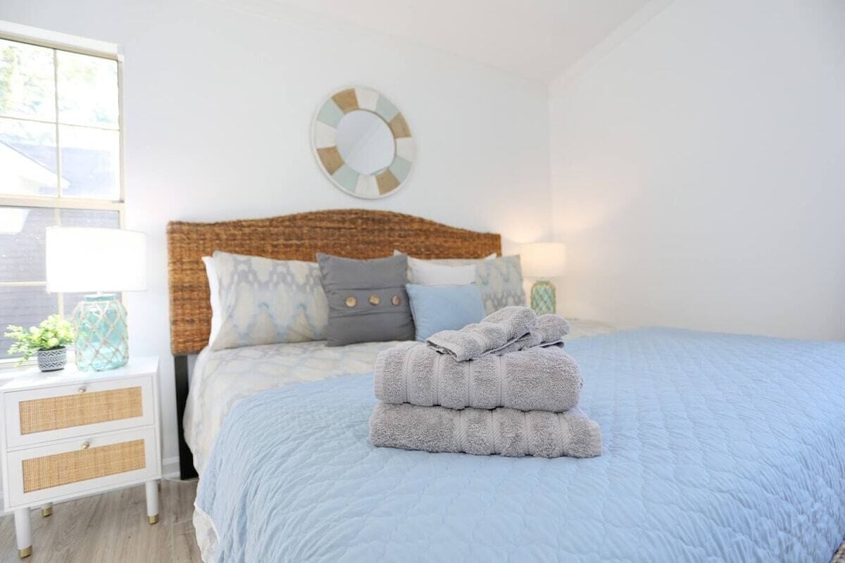 Un dormitorio con cama, mesita de noche, lámpara y decoración en la pared.