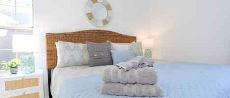 Un dormitorio con cama, mesita de noche, lámpara y decoración en la pared.