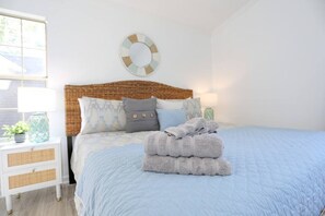 Una camera da letto con un letto, un comodino, una lampada e un elemento decorativo al muro.