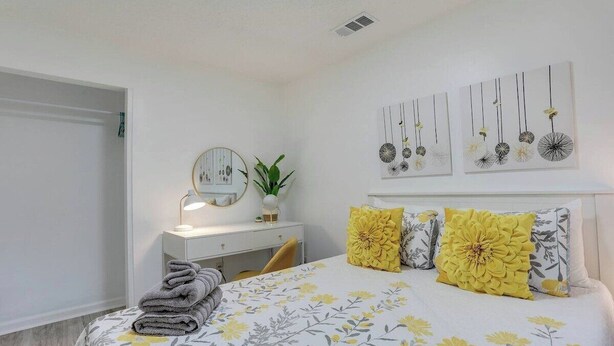 Un dormitorio con cama, mesita de noche, espejo y decoración en la pared.