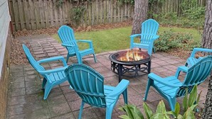 Un patio con cuatro sillas azules dispuestas alrededor de una mesa redonda y una chimenea en el centro.