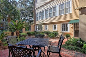 A patio with a table and chairs, surrounded by greenery and a building with multiple windows. - Downtown Savannah * Fun Studio on Jones Street * Walk to Forsyth * Dogs OK (Savannah)