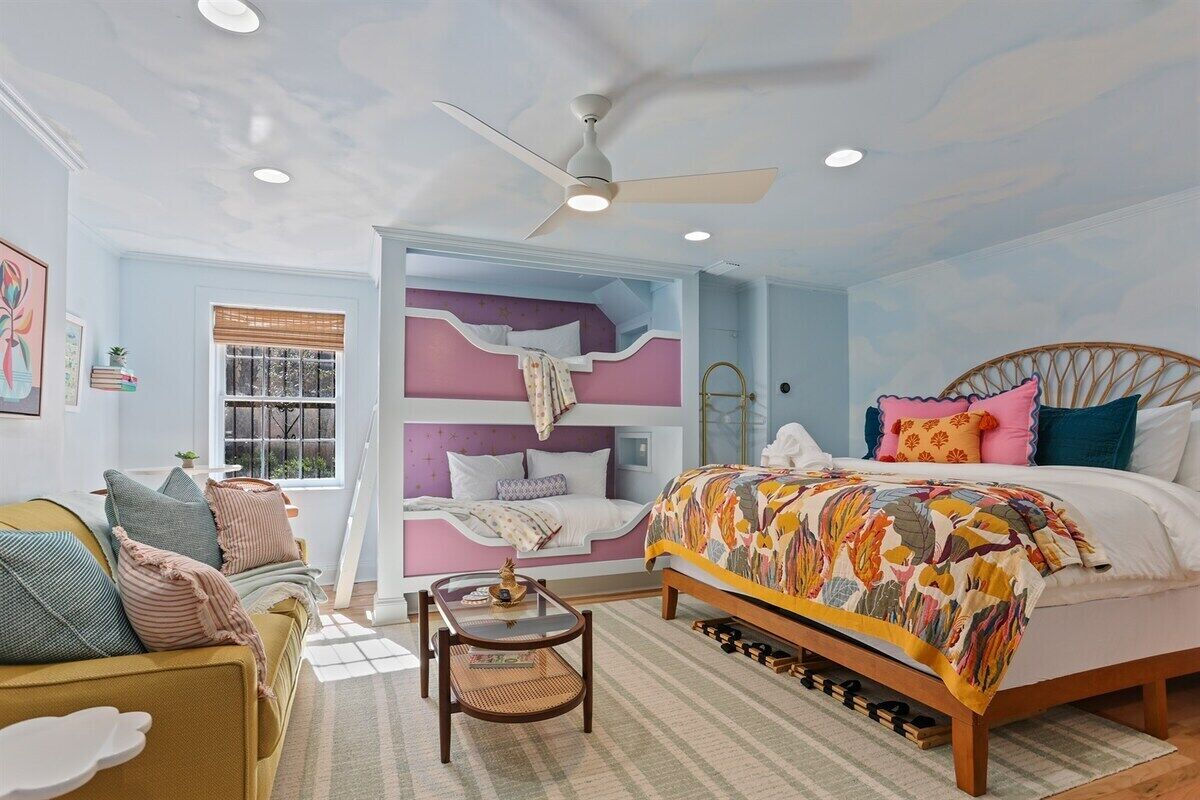 A bedroom with a bed, a window, a ceiling fan, and a sofa.