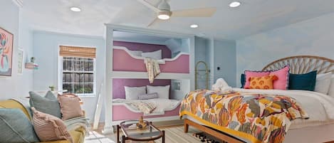 A bedroom with a bed, a window, a ceiling fan, and a sofa.