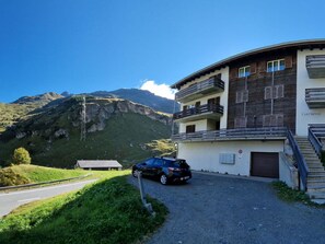 A building with a parking area, a car, and a mountainous landscape in the background. - Curtinfess Franklin Appartement/Fewo, Bad, WC, 2 Schlafräume by Interhome (Bivio)